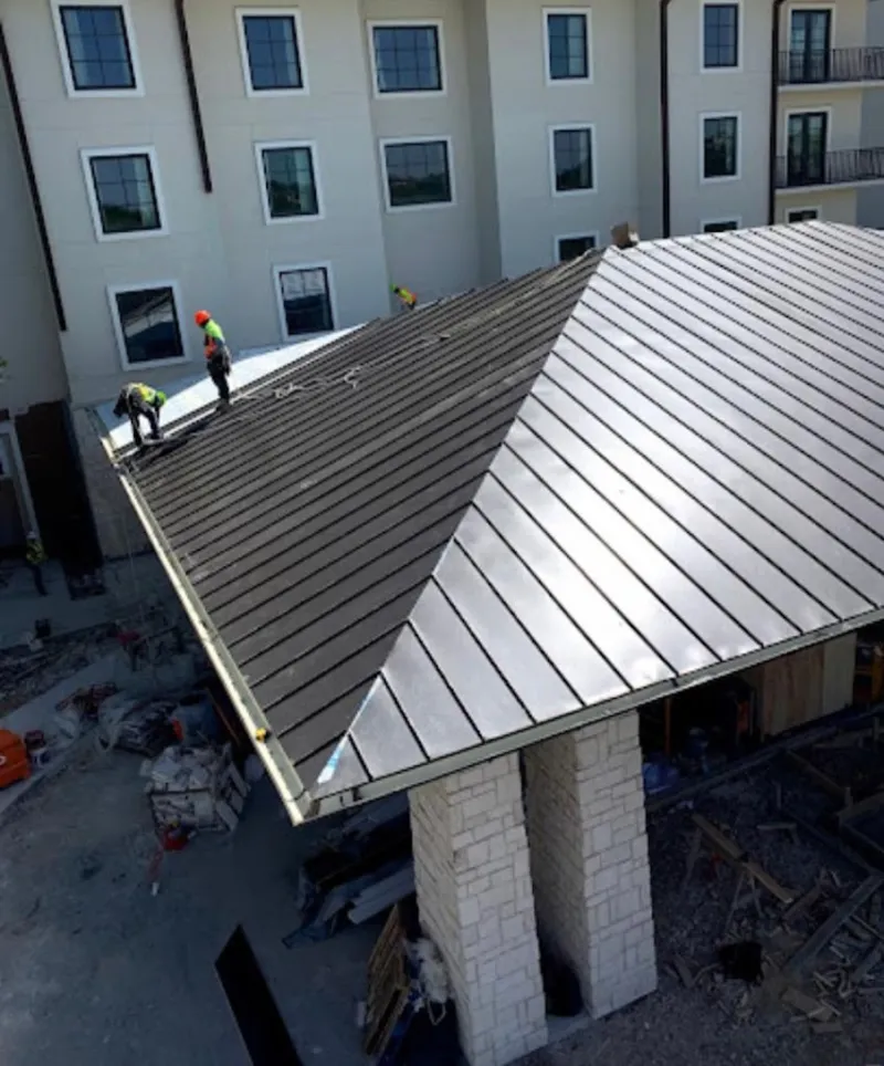 Crew installing standing seam metal roof panels on a commercial project in Kingman